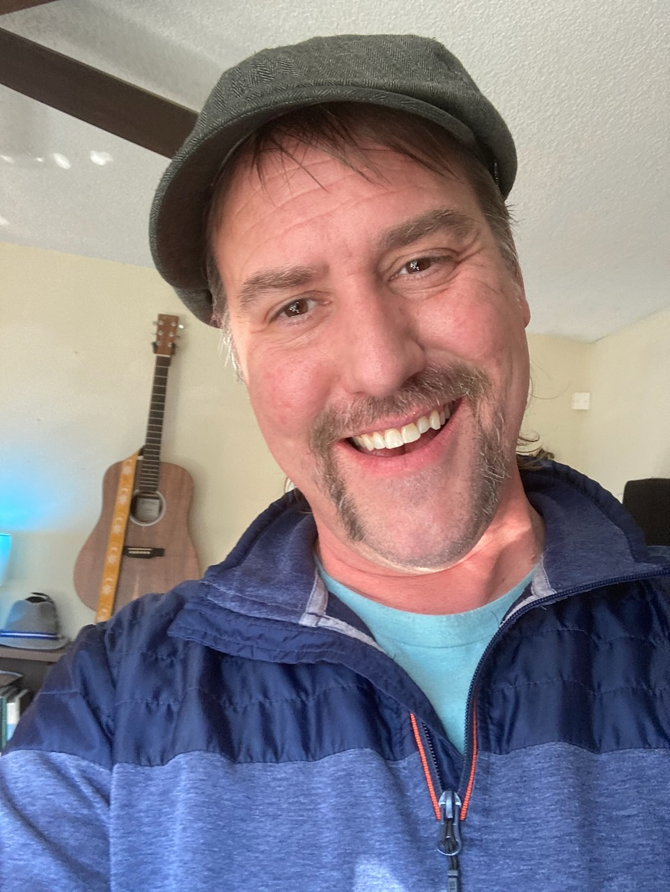 Collin Poseley smiling, with a guitar in the background