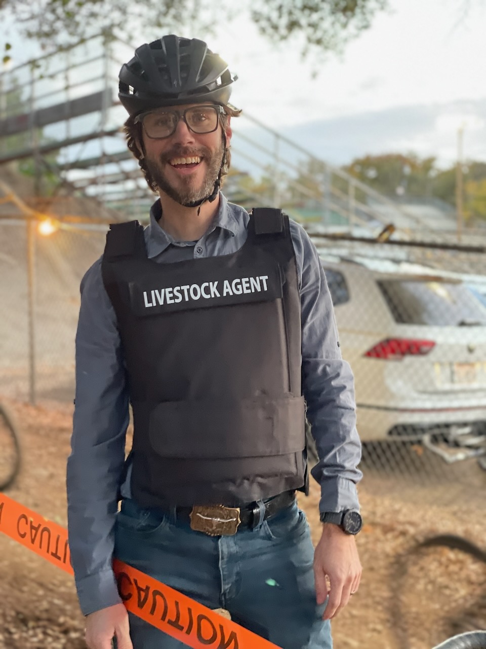 Nick Almond smiling outdoors, wearing glasses and a bicycle helmet